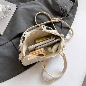 Interior capacity display of cream Boston bag showing phone, earphones, and cosmetics