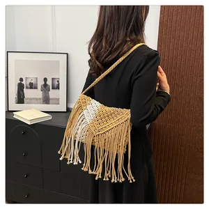Detail of bohemian woven straw bag with tassels and bicolor texture on a model