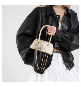 Lifestyle shot of model wearing the champagne snakeskin shell bag with metal chain strap