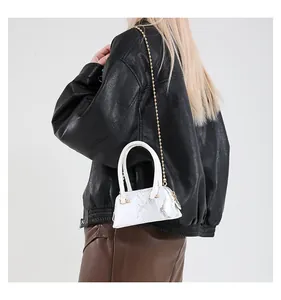 Detailed view of mini shell bag with silver snakeskin texture and gold chain on model