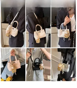Nahaufnahme einer glänzenden Mini-Handtasche mit Metallschloss und Plüschbär-Anhänger