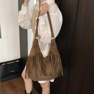 Brown suede bohemian shoulder bag with long fringe and gold metal rings shown on a model