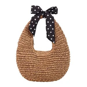 Handwoven half-moon straw handbag featuring a stylish polka dot silk scarf handle