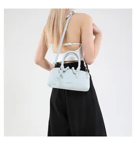 Back view of a light blue bowling-style tote bag worn by a model in a studio setting