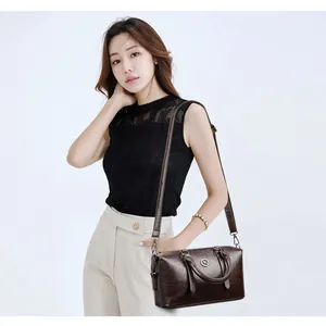 Minimalist brown pebbled leather Boston bag with silver hardware and shoulder strap