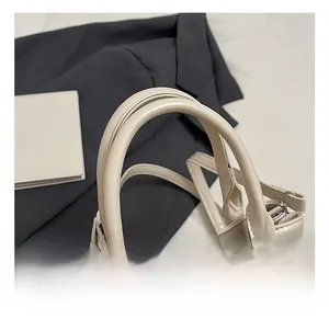 Detail der cremefarbenen Ledertasche mit runden Griffen und Metall-Drehverschluss