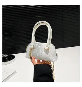 Detailed macro view of white snake skin texture and gold bead chain on mini shell bag