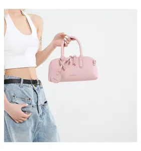 Detail of light pink leather tote bag with gold fashion logo and textured finish