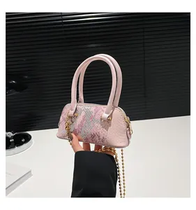 Detail of pink sequins and snake texture on shell bag with golden ball chain strap