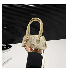 Detail of sequin shell bag featuring snake-patterned texture and gold ball chain strap