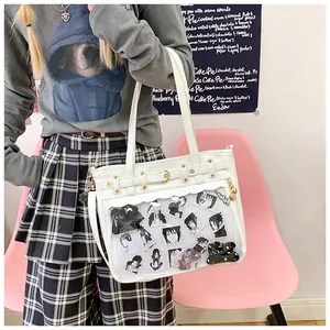 Bolso Ita de cuero blanco con ventana transparente y remaches en el hombro de una modelo