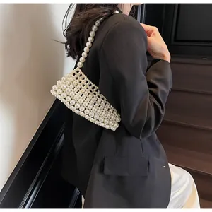 Detail of hand-woven white pearl crossbody bag styled with a chic black blazer