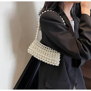 Detail of handcrafted white pearl woven handbag on black blazer with pearl strap