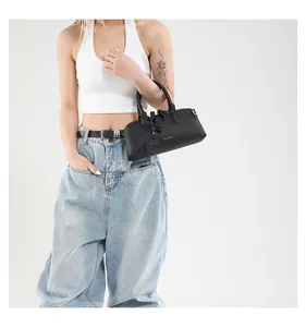 Detail of black litchi grain leather tote bag with gold FASHION text and round charm