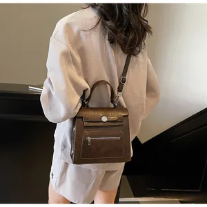 Detail of dark brown vintage faux leather crossbody bag with metal buckle and strap