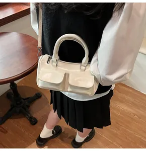 Detail view of cream polished leather shoulder bag with front pockets and silver hardware