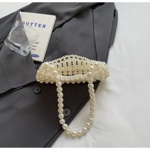 Detailed overhead shot of handmade pearl woven crossbody bag on grey blazer