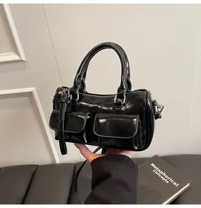 Detailed macro of black glossy leather handbag featuring dual pockets and silver hardware