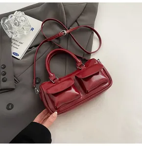 Detail of burgundy glossy leather shoulder bag with silver hardware and front pockets
