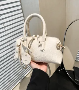 Close-up of white lychee pattern leather bowling bag with twin zippers and long tassels
