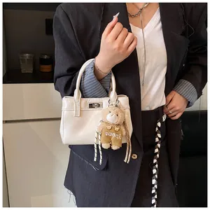 Detail einer weißen Mini-Handtasche mit Silber-Metallverschluss und süßem Bärenanhänger