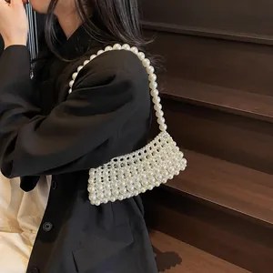 Handmade pearl beaded crossbody bag for women on a black blazer with wooden backdrop
