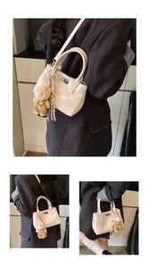 Detail der cremefarbenen Handtasche mit Drehverschluss und Teddybär-Anhänger