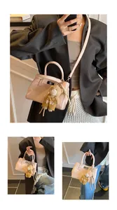 Detail der glänzenden rosa Handtasche mit silbernem Drehverschluss und Bärenanhänger