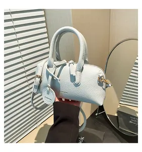 Detail of light blue lychee texture barrel bag with gold hardware and FASHION logo