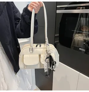 Dettaglio della borsa Boston crema con zip metallica, tasche anteriori e pendenti alla moda