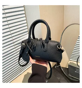 Detail of black lychee grain leather boston bag with gold fashion lettering and charm