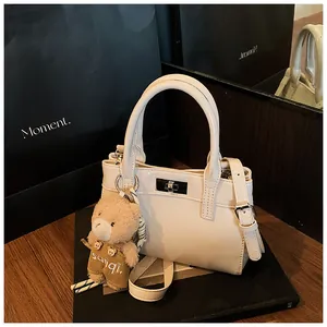 Detail der weißen Mini-Tasche aus Leder mit Silberverschluss und süßem Bärenanhänger