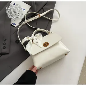 Detail of creamy white PU leather handbag with decorative floral scarf and metal turn-lock