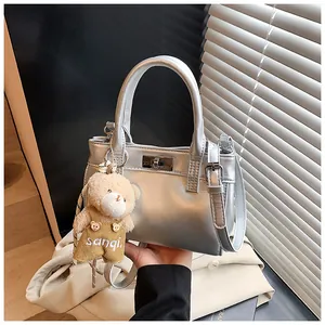Detailansicht der silbernen Handtasche mit Metalldrehverschluss und süßem Plüschbär