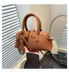 Detail showing brown lychee textured leather Boston bag with FASHION logo and tassel