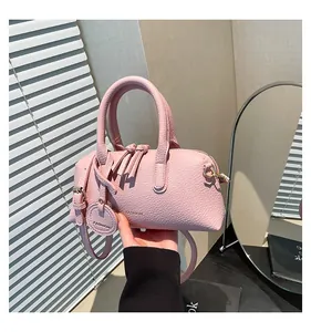 Detail of pink lychee grain leather tote bag featuring tassel charm and fashion logo