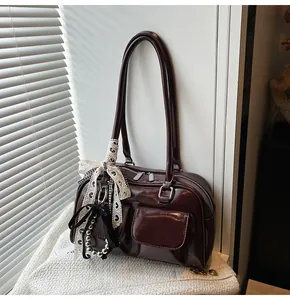 Dettaglio della borsa a spalla retrò rosso scuro con tasche frontali e ciondoli a fiocco