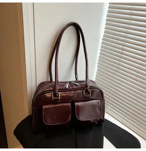 Dettaglio ravvicinato della borsa a spalla in pelle lucida marrone con due tasche frontali