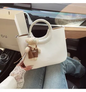 Detail van de witte lycheelederen handtas met gevlochten handvat en een schattige teddybeer