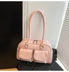 Dettaglio della borsa Boston rosa lucida con doppie tasche frontali e cerniere in metallo