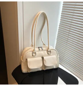 Dettaglio borsa Boston crema con tasche anteriori e finiture in metallo argentato