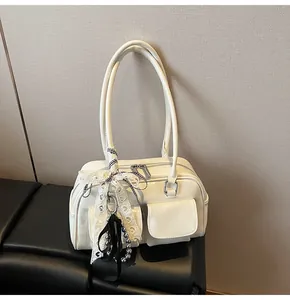 Dettaglio borsa Boston bianco crema con fiocco in pizzo e ciondolo di perle elegante