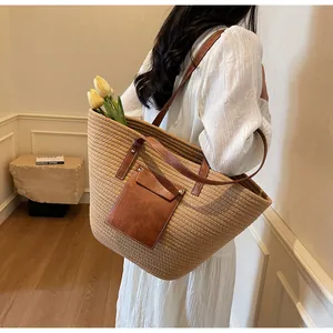 Détail d'un grand sac cabas en paille avec poche en cuir marron porté par un mannequin