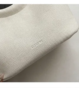 Makroaufnahme der weißen Handtasche aus Leder mit Litschimuster und CLEAR❤K Logo