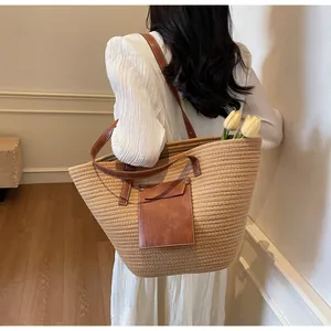 Détail d'un sac cabas en paille tissé avec anses en cuir marron et poche avant à rabat