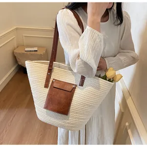Détail d'un sac cabas en paille tissée avec anses en simili cuir marron sur un mannequin