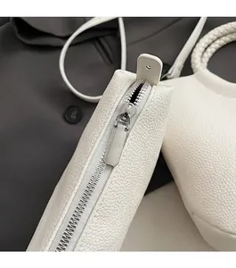 Nahaufnahme eines glatten Metallreißverschlusses an einer weißen Beuteltasche aus Leder