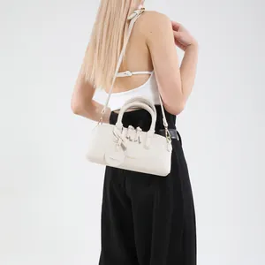 Chic off-white leather tote bag with gold lettering shown on a model in a minimalist studio