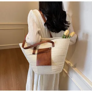 Détail d'un sac cabas tissé crème avec lanières en cuir marron et poche frontale