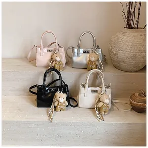Detailansicht von vier Mini-Umhängetaschen in Rosa, Silber, Schwarz, Beige mit Bärenanhänger
